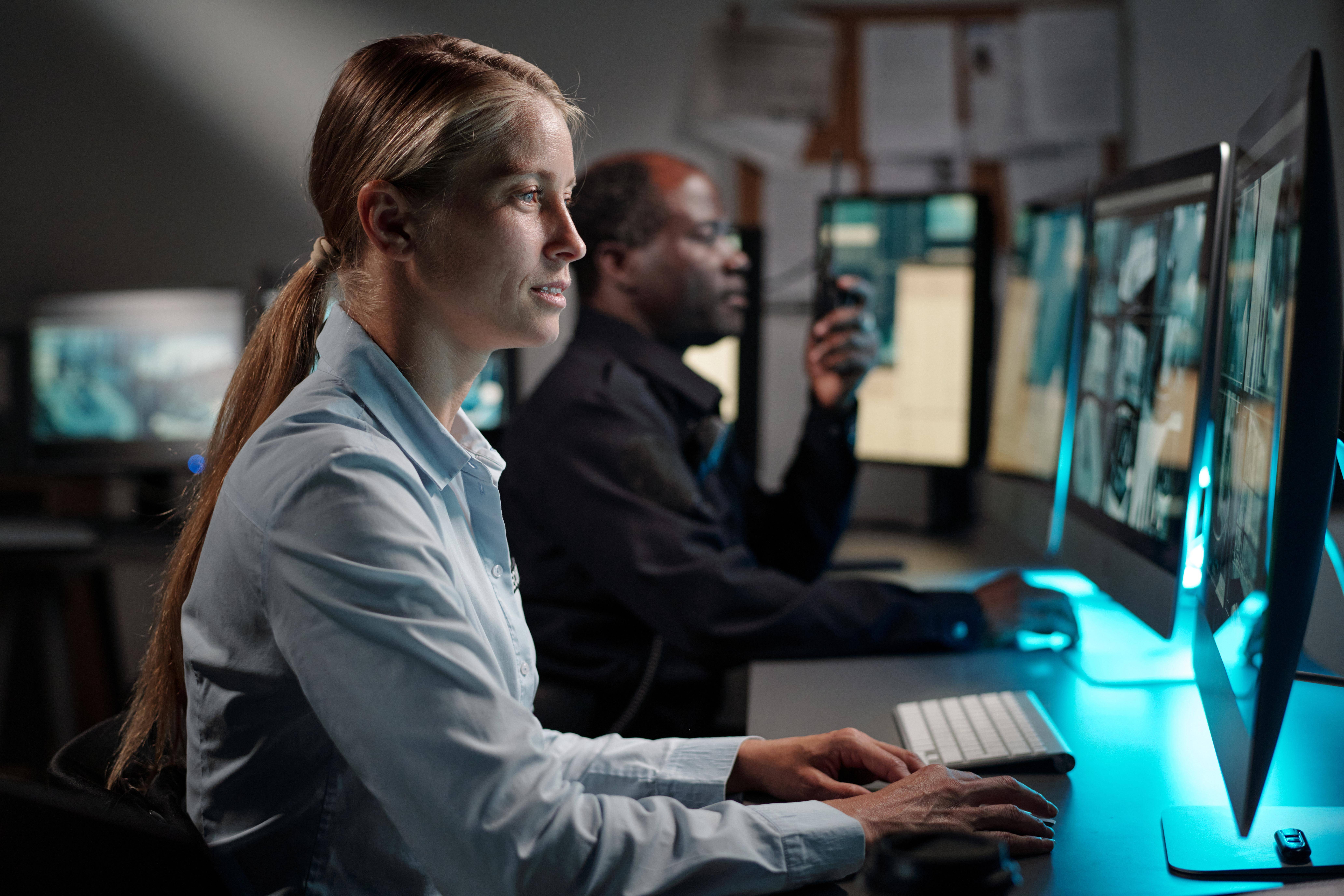 Dos personas trabajando en un entorno tecnológico en diversas pantallas de computadora.