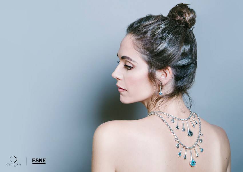 Una mujer con un peinado elegante y joyas brillantes que adornan su cuello y espalda.