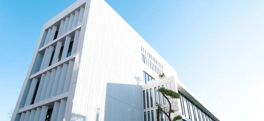 Edificio moderno con una fachada blanca y diseño minimalista bajo un cielo despejado.