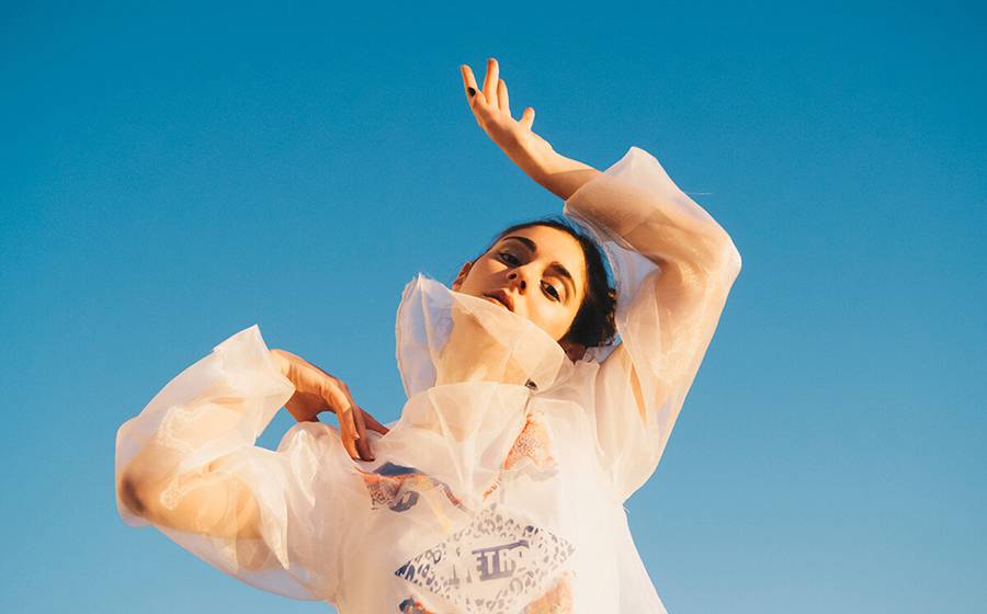 Una mujer posando en una postura artística bajo un cielo azul claro.