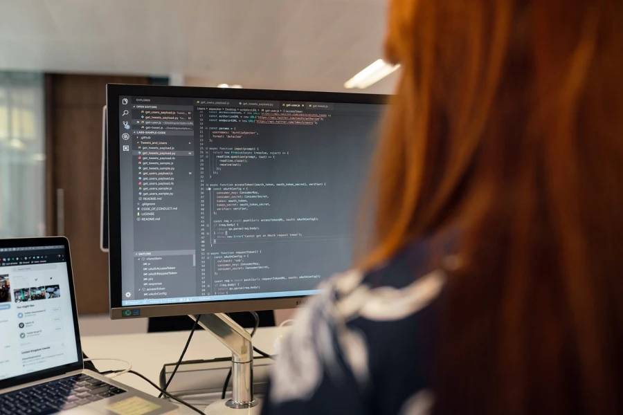 Una persona está programando en un ordenador mientras observa líneas de código en la pantalla.