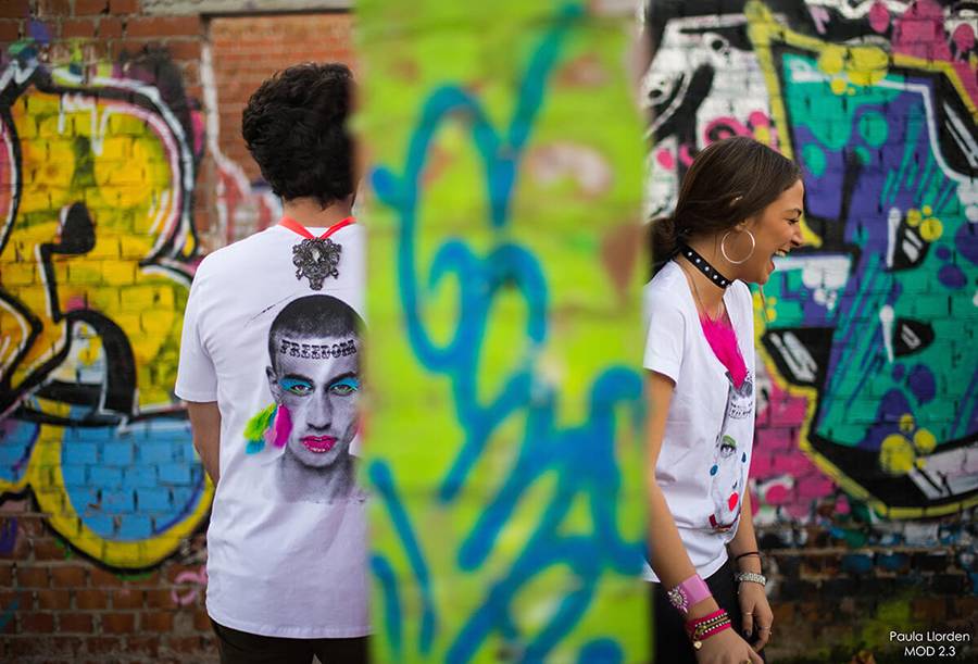 Dos personas están de espaldas frente a un mural colorido lleno de grafitis.