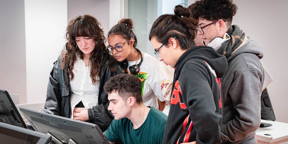 Un grupo de jóvenes se concentra en una pantalla de computadora en un entorno de aprendizaje.