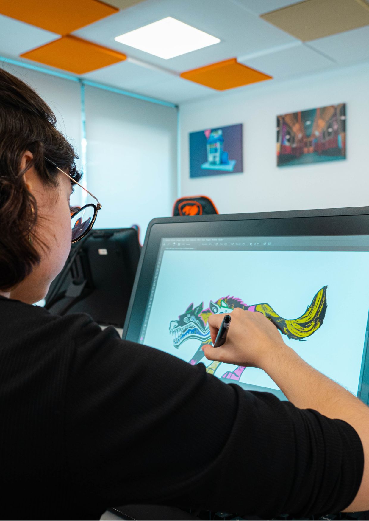 Una persona está dibujando en una tableta digital un animal con colores vivos en un entorno de oficina.