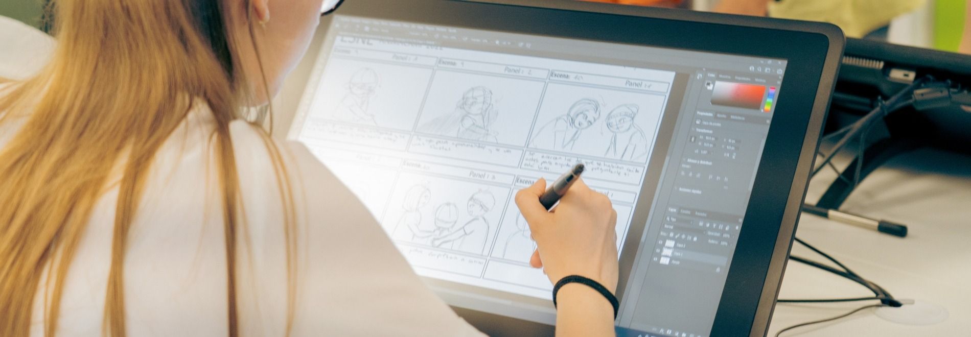 Una persona está dibujando en una tableta gráfica con varias viñetas en pantalla.