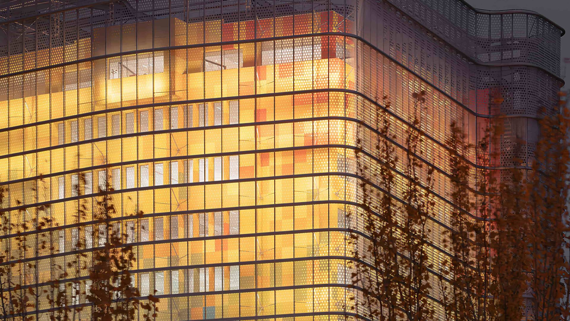 Edificio moderno con fachadas de vidrio y colores cálidos al atardecer.