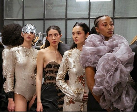Un grupo de modelos luciendo trajes de diseño en un ambiente de ensayo de moda.