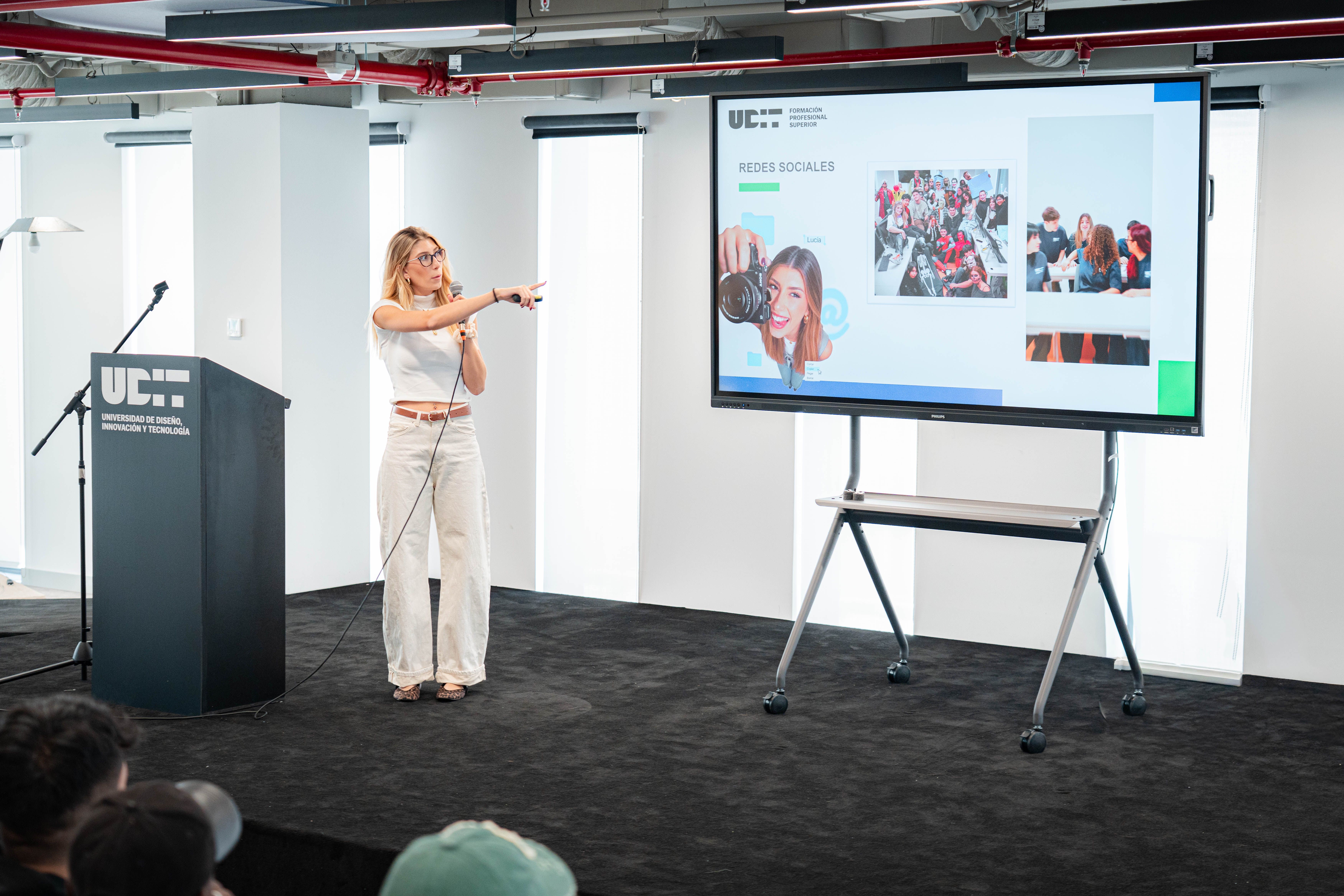Una presentadora señala una diapositiva sobre redes sociales en un evento.