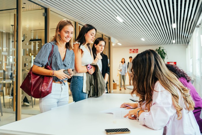 Un grupo de mujeres en un ambiente de oficina, esperando su turno en un mostrador.