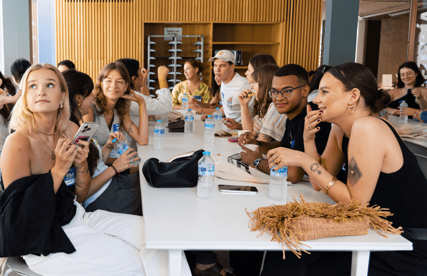 Un grupo de jóvenes se encuentra conversando y socializando en una mesa en un ambiente moderno.