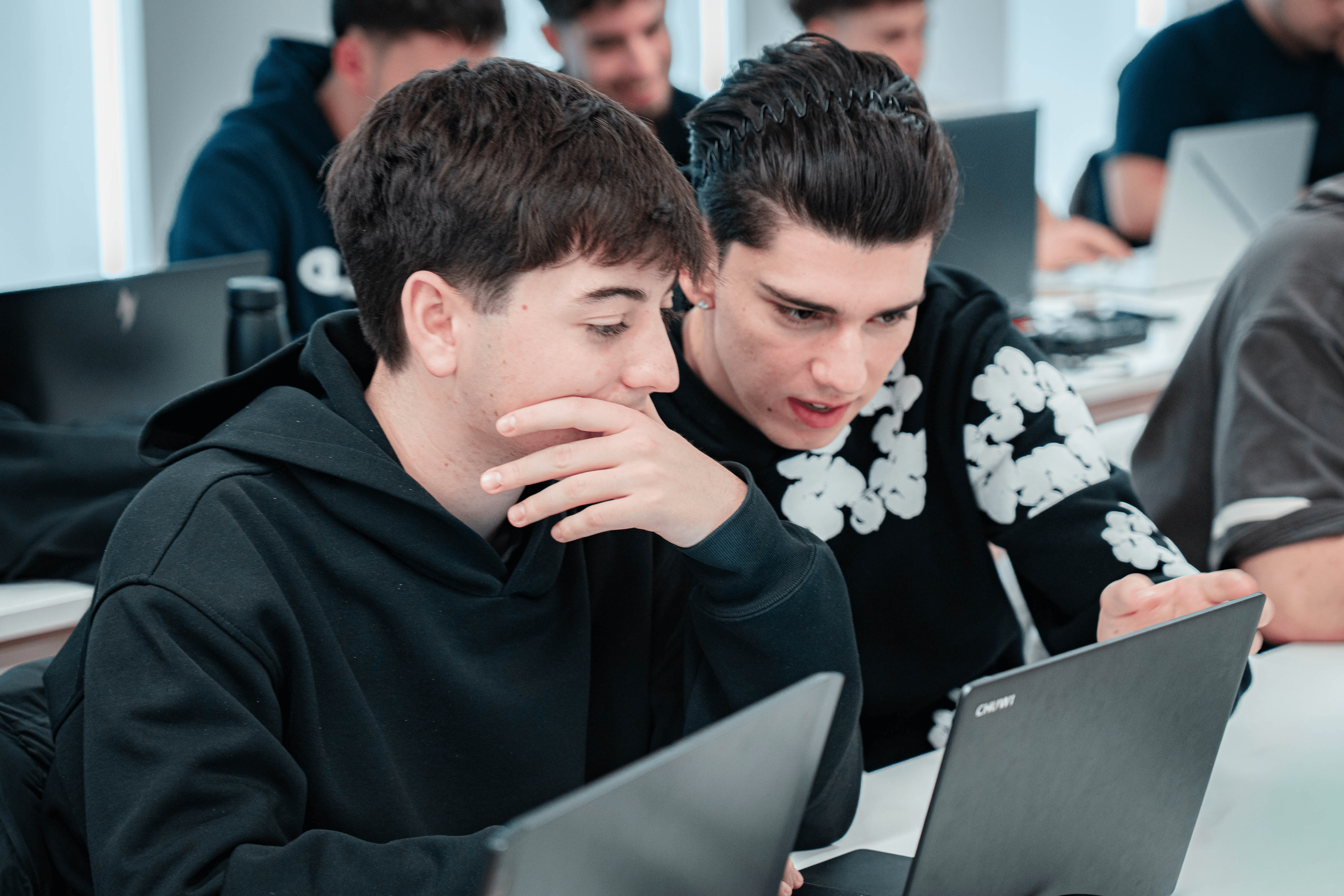 Dos jóvenes concentrados en una computadora portátil en un entorno de aprendizaje.